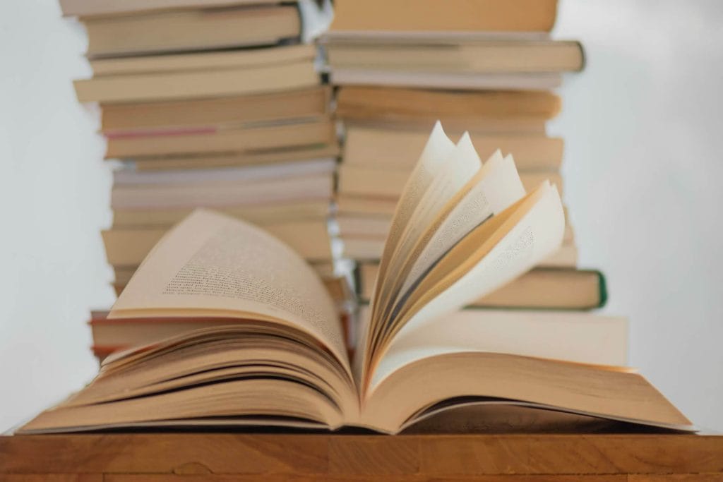 Several open books stacked together with pages spread out.