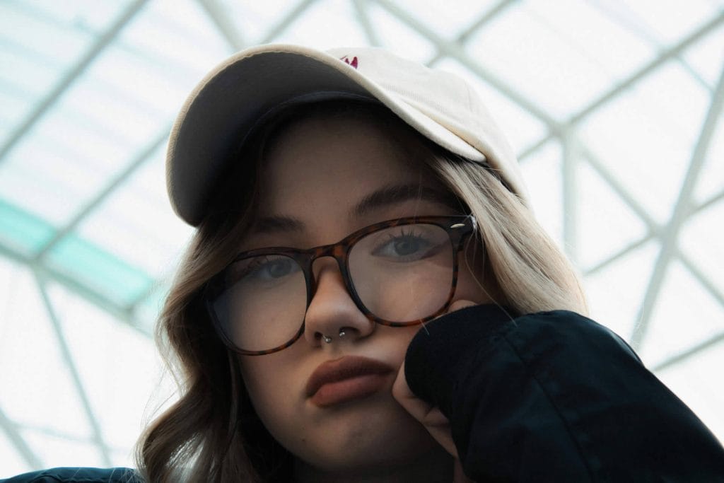 Thoughtful woman in glasses resting her chin on her hand, appearing deep in thought.