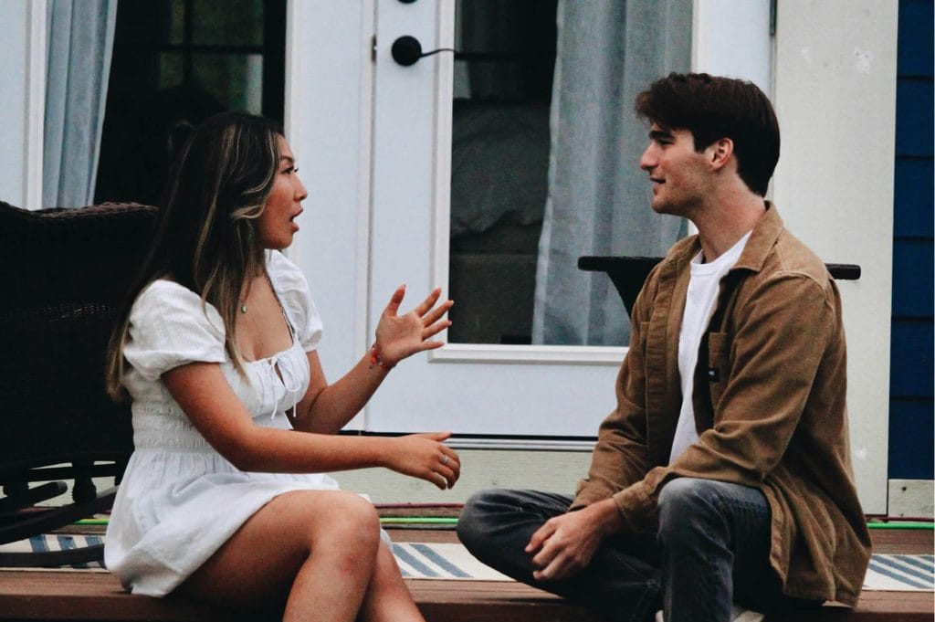 Two people sitting on outdoor steps having an animated conversation.