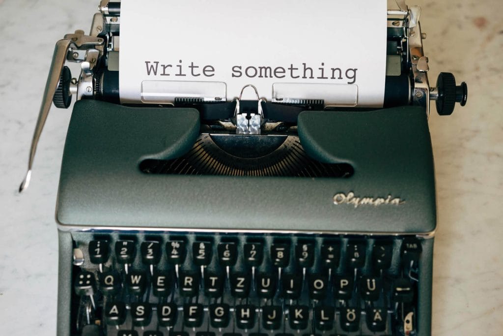 Vintage typewriter with paper that says “Write something.”