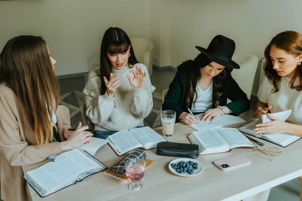 Two people collaborating at a table covered with notebooks and coffee cups.